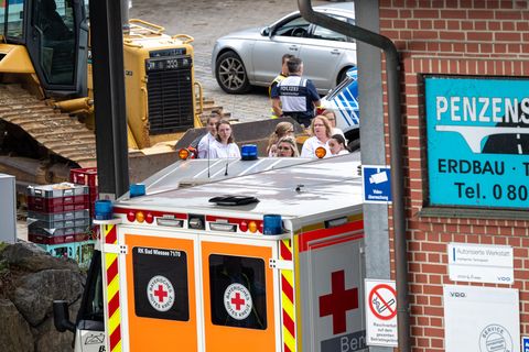 Rettungskräfte stehen auf einem Betriebshof in Bayern, wo drei Arbeiter in einem Kanalschacht ertrunken sind