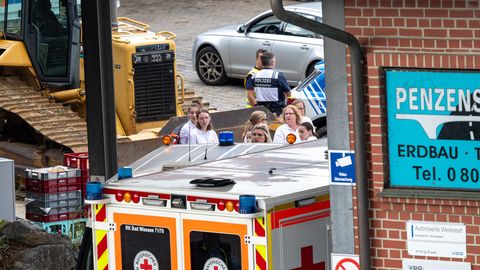 Rettungskräfte stehen auf einem Betriebshof in Bayern, wo drei Arbeiter in einem Kanalschacht ertrunken sind
