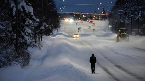 Mann läuft beschneite Straße in Anchorage, Alaska entlang
