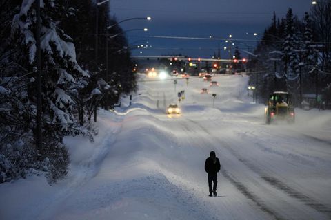 Mann läuft beschneite Straße in Anchorage, Alaska entlang