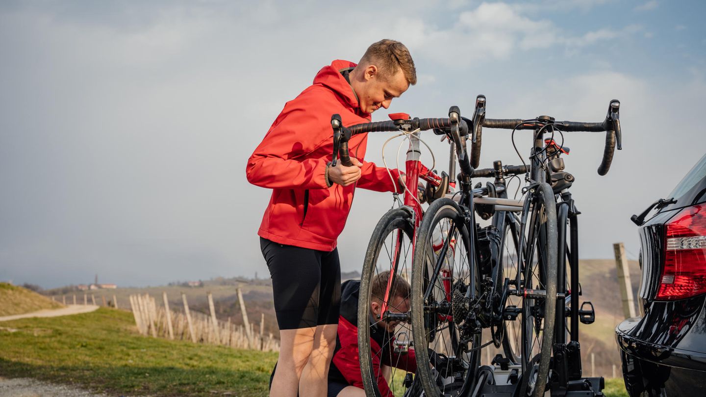 Mann befestigt Fahrrad auf Fahrradträger