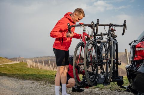 Mann befestigt Fahrrad auf Fahrradträger