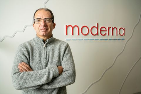 Stéphane Bancel, Chef der US-amerikanischen Pharmafirma Moderna, steht mit verschränkten Armen vor dem Logo des Unternehmens.