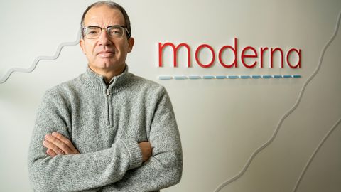 Stéphane Bancel, Chef der US-amerikanischen Pharmafirma Moderna, steht mit verschränkten Armen vor dem Logo des Unternehmens.