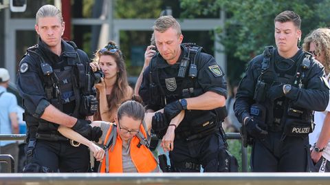 Polizisten tragen eine Klimaaktivistin weg