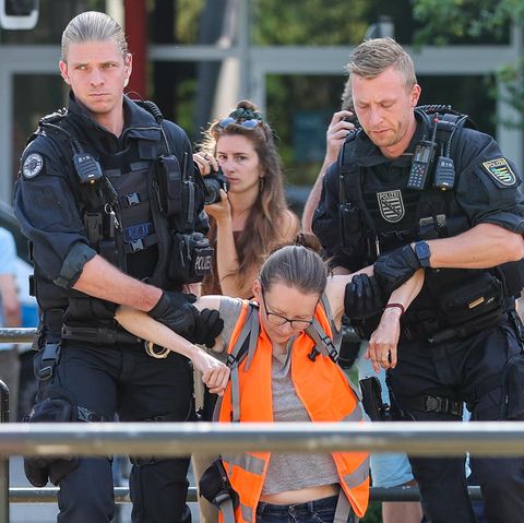 Polizisten tragen eine Klimaaktivistin weg
