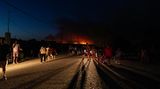 Rhodos: Menschen auf der Straße,  im Hintergrund sind Flammen