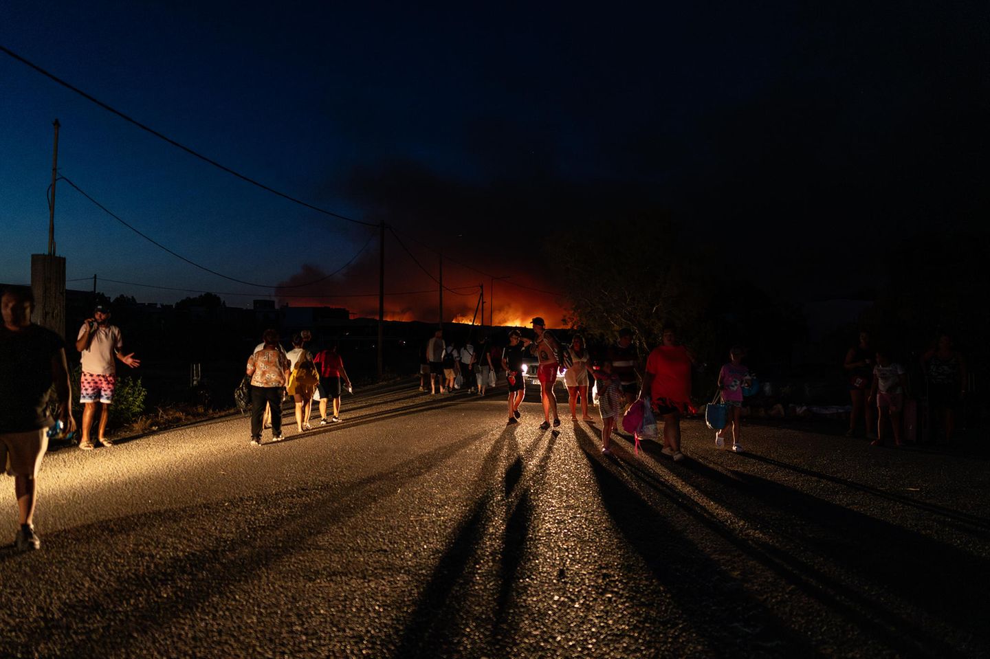Rhodos: Menschen auf der Straße,  im Hintergrund sind Flammen