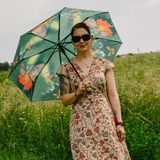 Frau im Blumenkleid mit Sonnenschirm und Sonnenbrille