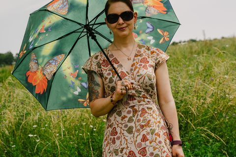 Frau im Blumenkleid mit Sonnenschirm und Sonnenbrille