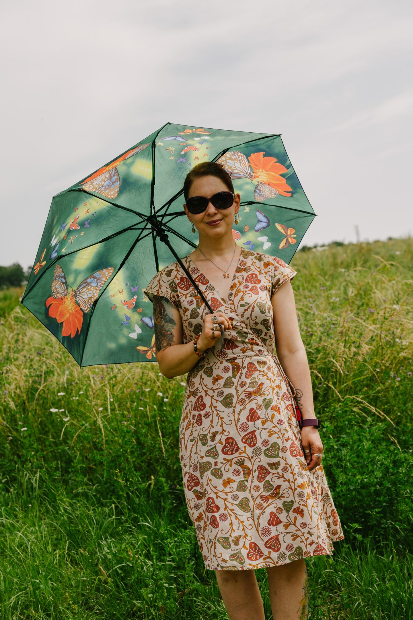 Frau im Blumenkleid mit Sonnenschirm und Sonnenbrille Frau im Blumenkleid mit Sonnenschirm und Sonnenbrille