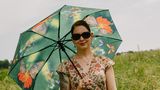 Frau im Blumenkleid mit Sonnenschirm und Sonnenbrille
