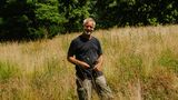 Mann im schwarzen T-Shirt steht vor Wiese