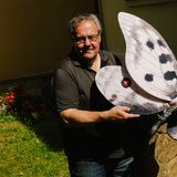 Mann mit Schnurrbart hält Modell eines Apollofalters