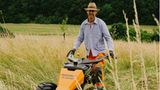 Mann mit orangefarbener Arbeitshose und hellbeigem Hemd und Sonnenhut
