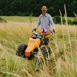 Mann mit orangefarbener Arbeitshose und hellbeigem Hemd und Sonnenhut