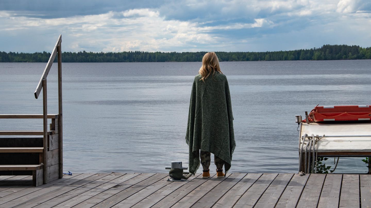 Eine Frau steht auf einem Steg am See. Eine Frau steht auf einem Steg am See.