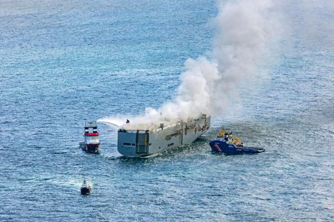 Eine Luftaufnahme zeigt den einen Notschlepper (l.), der den Brand auf einem Frachter im Meer bekämpft