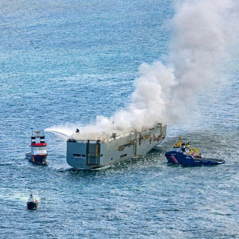 Eine Luftaufnahme zeigt den einen Notschlepper (l.), der den Brand auf einem Frachter im Meer bekämpft