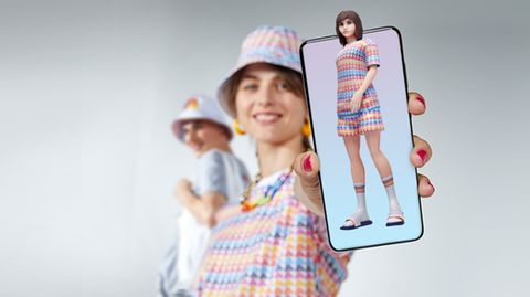 Frau hält Smartphone, auf dem ein Avatar zu sehen ist, in die Kamera
