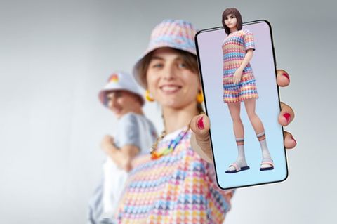 Frau hält Smartphone, auf dem ein Avatar zu sehen ist, in die Kamera