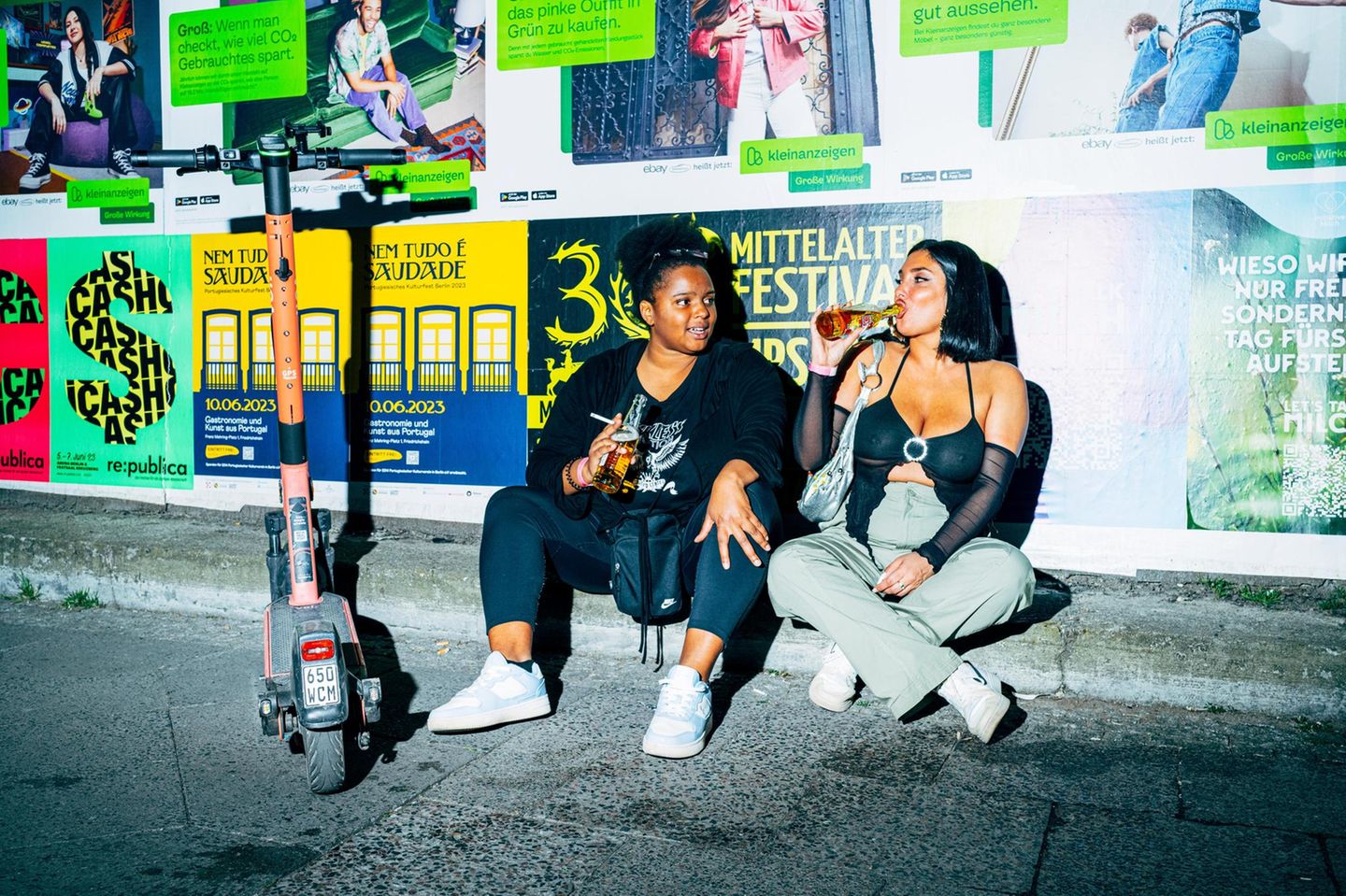 Zwei Frauen sitzen mit Bier auf der Straße