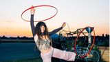 Eine Frau mit mehreren Hula-Hoop Reifen im Sonnenuntergang