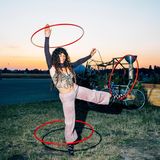 Eine Frau mit mehreren Hula-Hoop Reifen im Sonnenuntergang