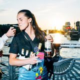 Eine junge Frau lässt sich Zigarette anzünden und steht auf einer Brücke mit Wein und Bier