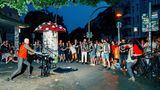 Ein Straßenkünstler und viele Menschen stehen um ihn herum