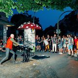 Ein Straßenkünstler und viele Menschen stehen um ihn herum