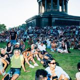 Viele Menschen sitzen auf einer Wiese