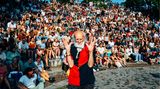Ein alter Mann ist im Vordergrund im Hintergrund sitzen viele Menschen auf Stufen