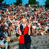 Ein alter Mann ist im Vordergrund im Hintergrund sitzen viele Menschen auf Stufen