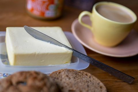 Butter auf dem Frühstückstisch, daneben eine Kaffeetasse, im Vordergrund Brot