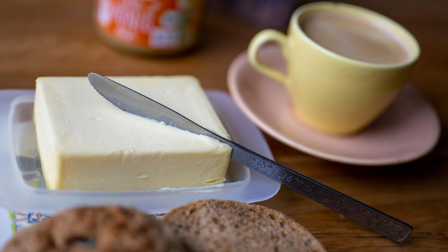 Butter auf dem Frühstückstisch, daneben eine Kaffeetasse, im Vordergrund Brot