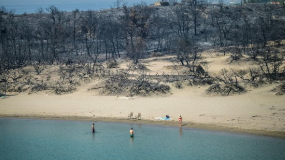 Touristen an einem von Waldbränden betroffenen Strand