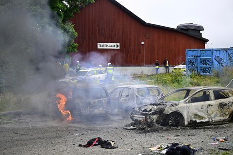Polizisten stehen neben ausgebrannten Autos während des eritreischen Kulturfestivals "Eritrea Scandinavia" in Schweden