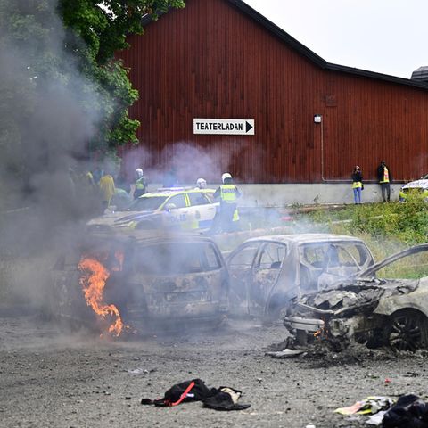Polizisten stehen neben ausgebrannten Autos während des eritreischen Kulturfestivals "Eritrea Scandinavia" in Schweden