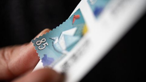Eine Frau löst eine 85 Cent Briefmarke von einem Bogen