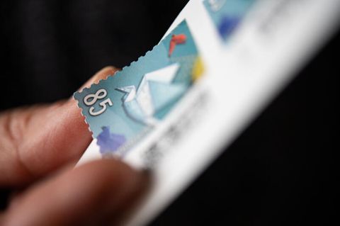 Eine Frau löst eine 85 Cent Briefmarke von einem Bogen