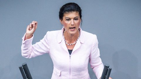Sahra Wagenknecht steht am Rednerpult des Deutschen Bundestages und hält beim Reden die rechte Hand hoch