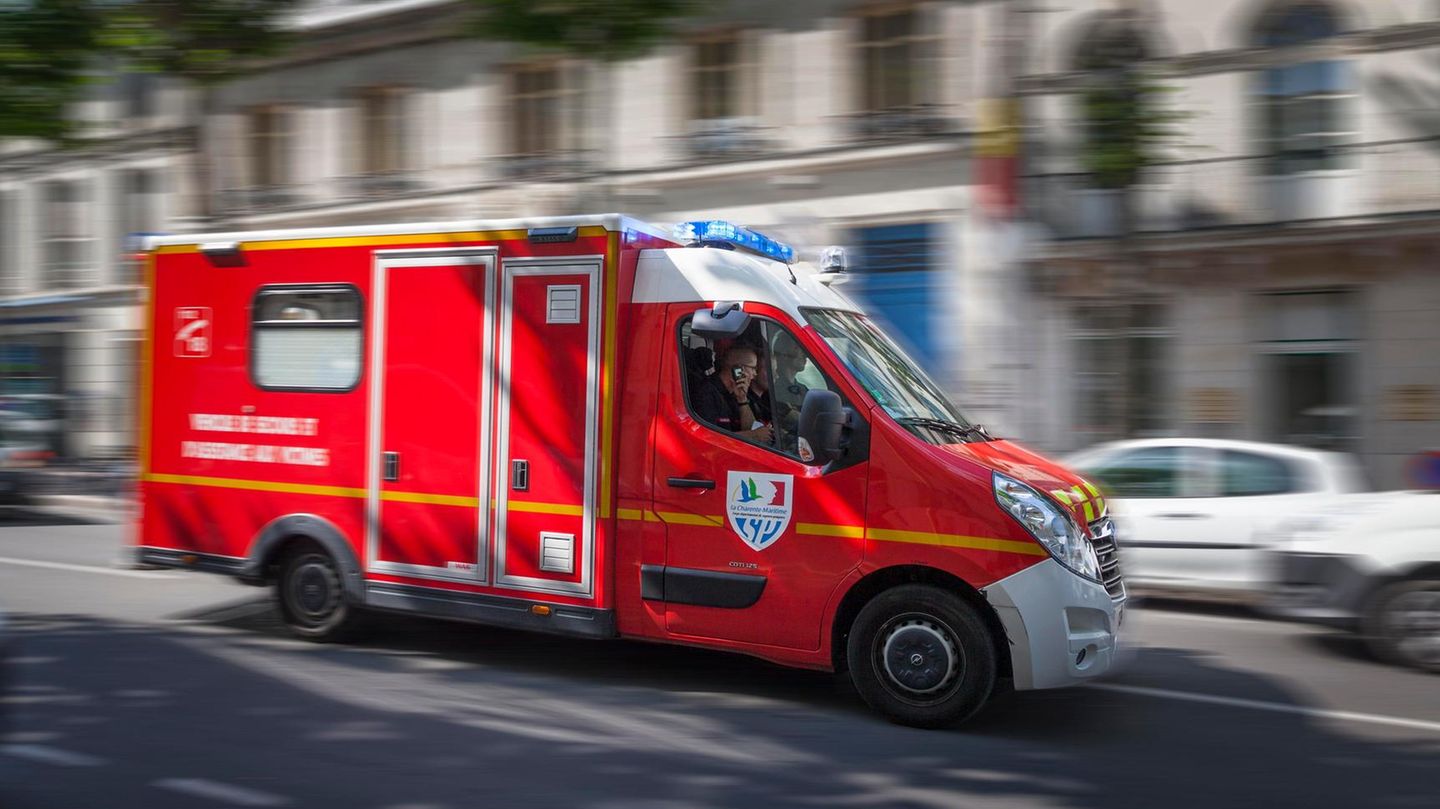 Ein roter Krankenwagen fährt mit Blaulicht durch eine Straße in Frankreich