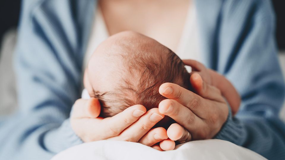 Thema Totgeburt: Zwei Hände halten den Kopf eines Neugeborenen