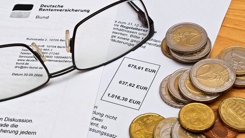 Rentenbescheid der Deutschen Rentenversicherung, auf dem eine Lesebrille und einige Euro-Münzen liegen