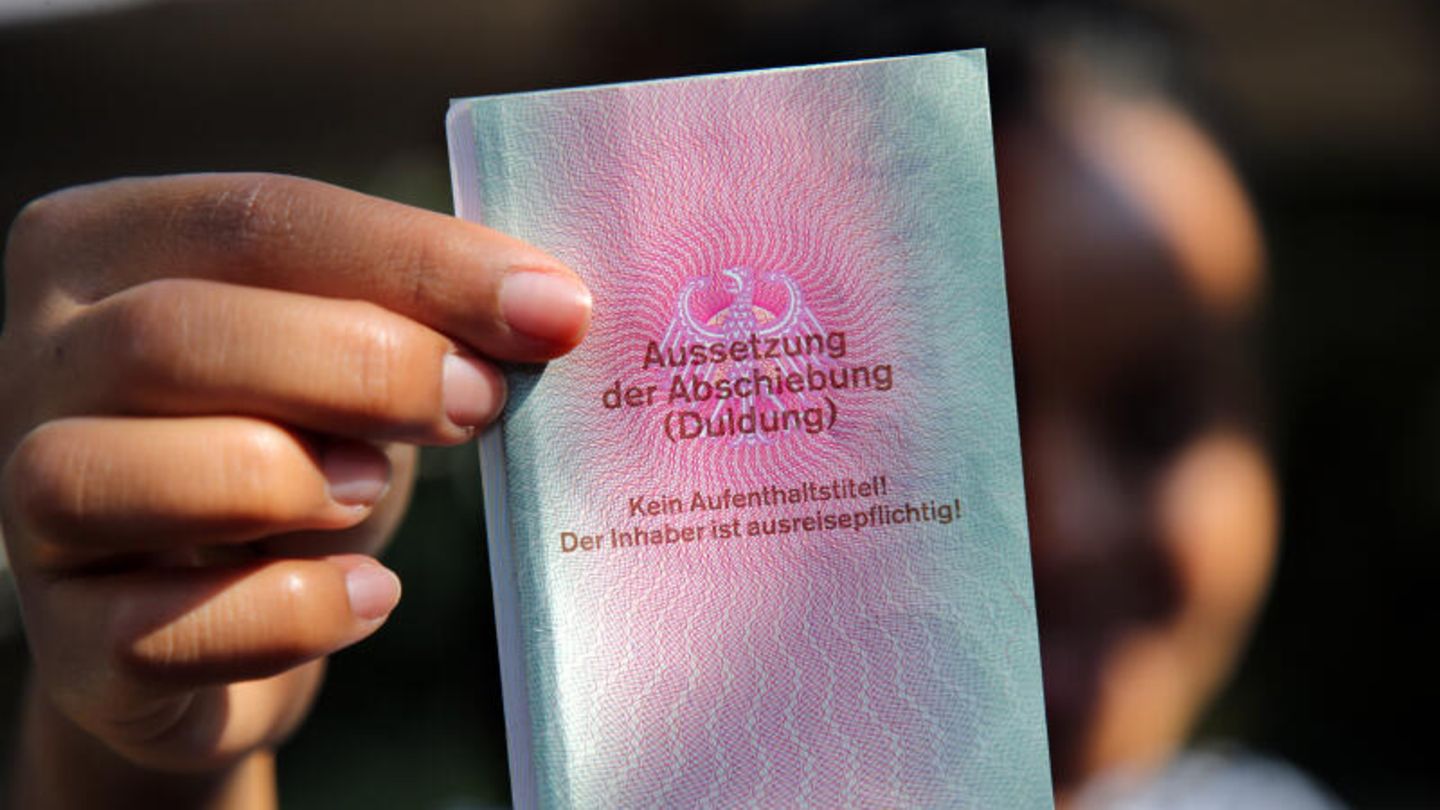 Eine junge Frau aus Afrika hält einen Ausweis für Flüchtlinge in der Hand mit dem Titel: Aussetzung der Abschiebung (Duldung)