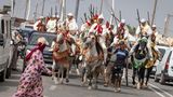 Vergangenheit trifft Gegenwart: Traditionell gekleidete Reiter auf dem Weg zur Fantasia