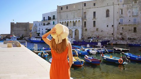 "Tomato Girls": Junge Frau in einem roten Kleid steht in einem Bootsanleger in Italien
