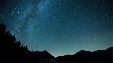 Eine Sternschnuppe leuchtet neben der Milchstraße am Himmel über dem Walchensee