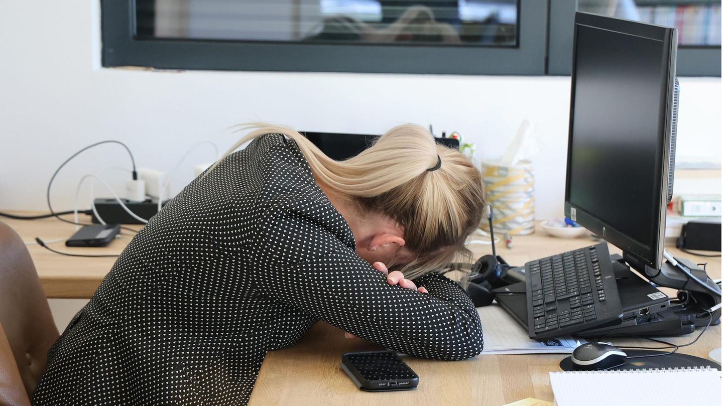 Eine Frau hat ihren Kopf auf ihren Schreibtisch aufgelegt
